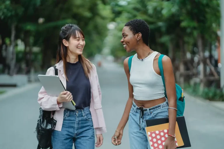 Female friends talking while standing on road. Friendship is one way promote international understanding and respect for diversity.