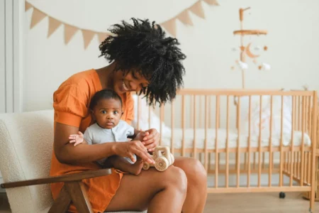 Woman Holding a Baby While Sitting on a Chair. Novotel Nairobi Honors Mothers with May Festivities