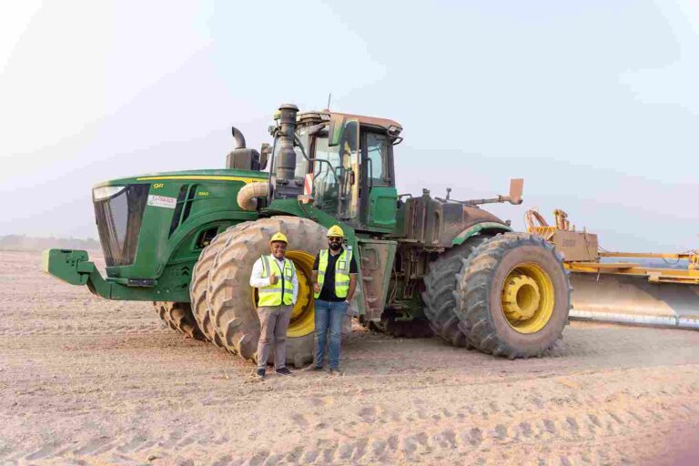 Mushagalusa and Fatania stand before levelling tractor at Jambo Farm
