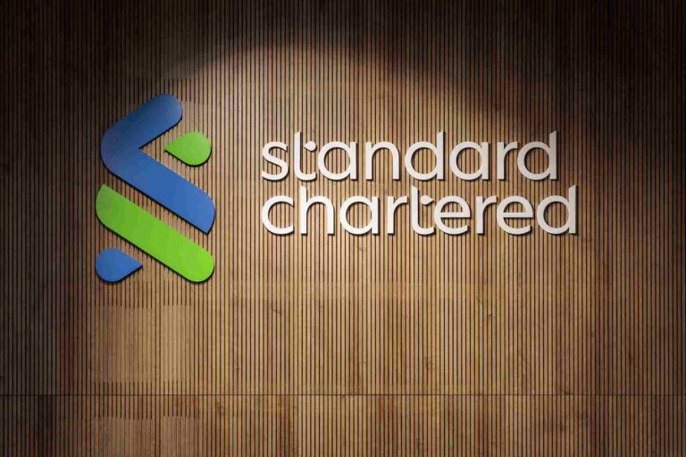 Absa Bank Uganda to Acquire Standard Chartered’s Wealth and Retail Unit Standard Chartered logo displayed on a wooden wall at a corporate office.