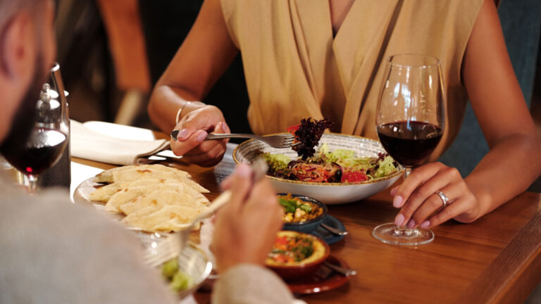 Diners eating at a busy restaurant table in East Africa, with food and drinks served
