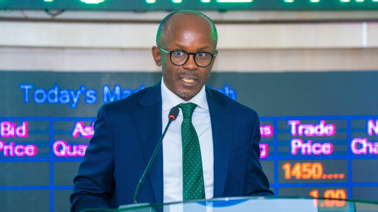 James Mworia, CEO of Centum Investment Company, speaking at a podium in front of a stock market ticker display.