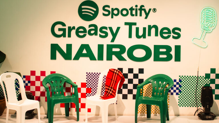 Spotify Greasy Tunes Nairobi wall logo behind green and white plastic chairs with a checkered backdrop
