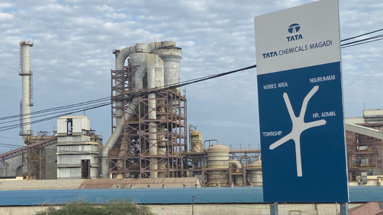 Tata Chemicals Magadi entrance sign with the soda ash processing plant and industrial towers in the background, Kajiado County, Kenya
