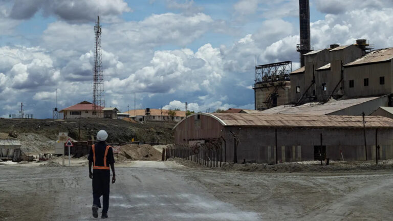 Tata Chemicals Magadi soda ash plant with a worker in safety gear walking toward the site in Kajiado County, Kenya.