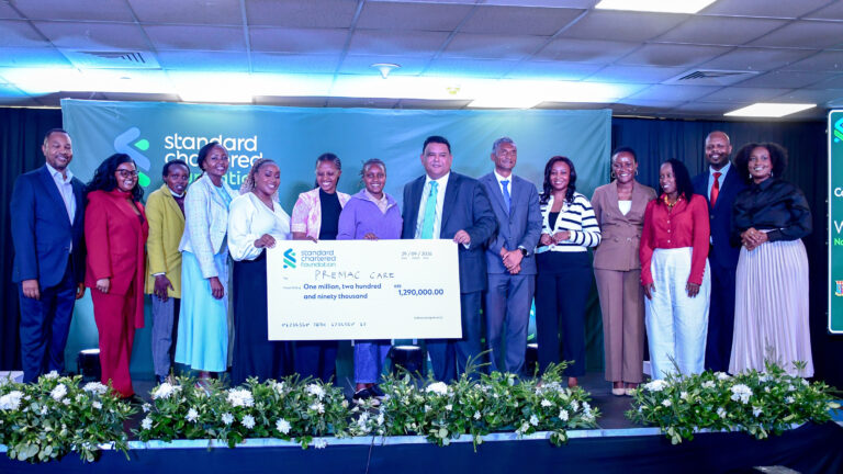 Women in Tech Kenya Cohort 9 winners and hosts on stage holding a KES 1,290,000 cheque made out to Premac Care