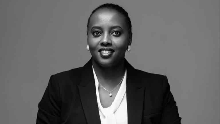 Black and white portrait of Diana Agaba Tukundane, seated in a dark blazer with her hands clasped.