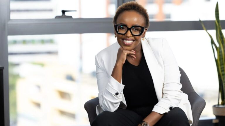 Rosalyn Mugoh, Managing Director of Heritage Insurance, seated by a window in a white blazer with her hand under her chin.