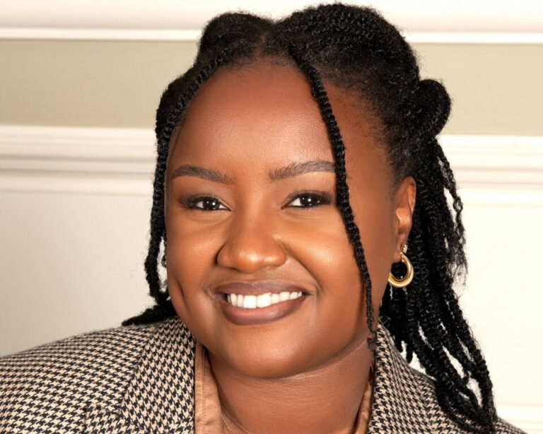 Wawira Njiru, founder and CEO of Food4Education, smiling in a houndstooth blazer against a cream wall.